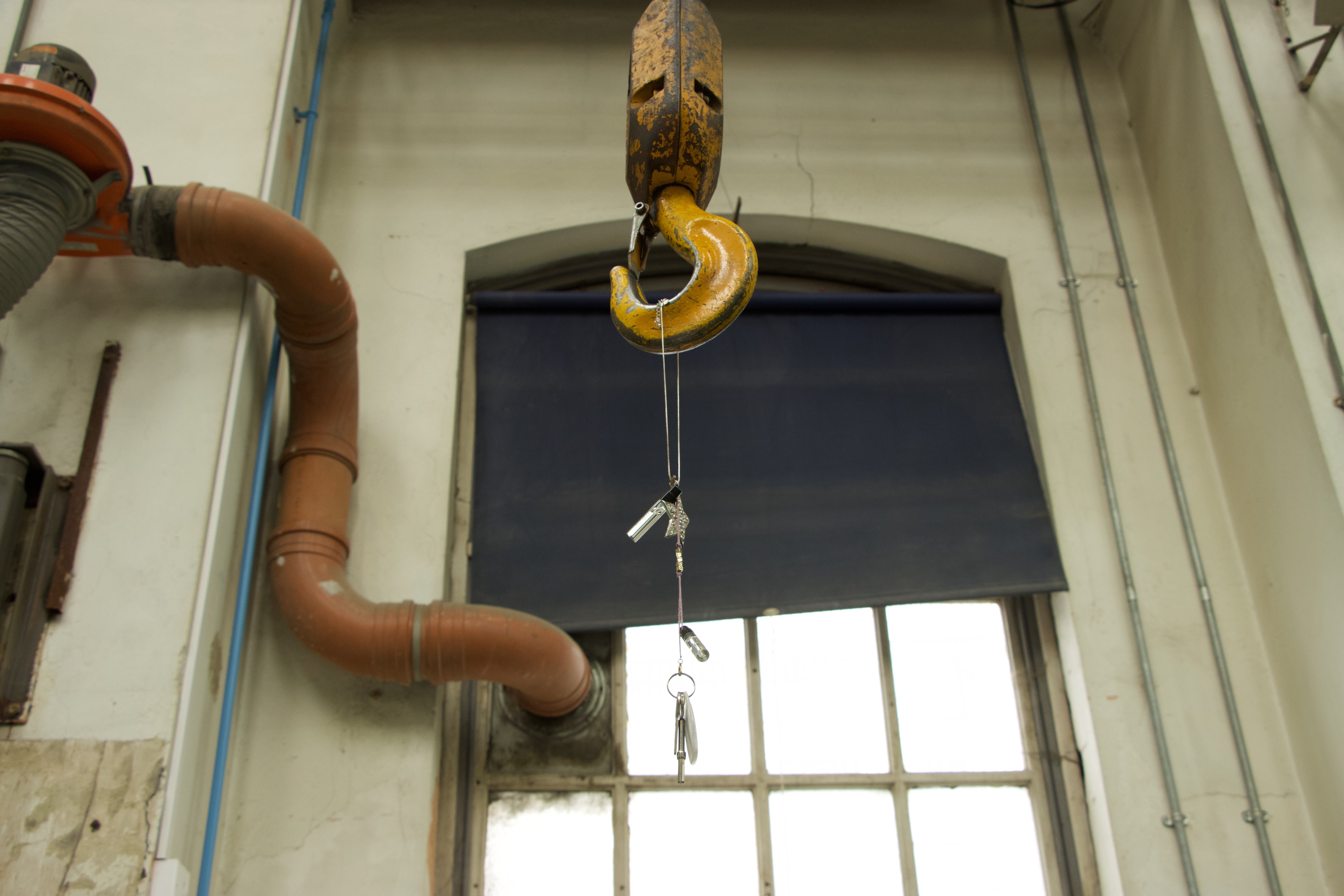 Necklace, bracelet, BYREDO perfume samples, Delta security keyring and keys hanging from a large yellow gantry hook