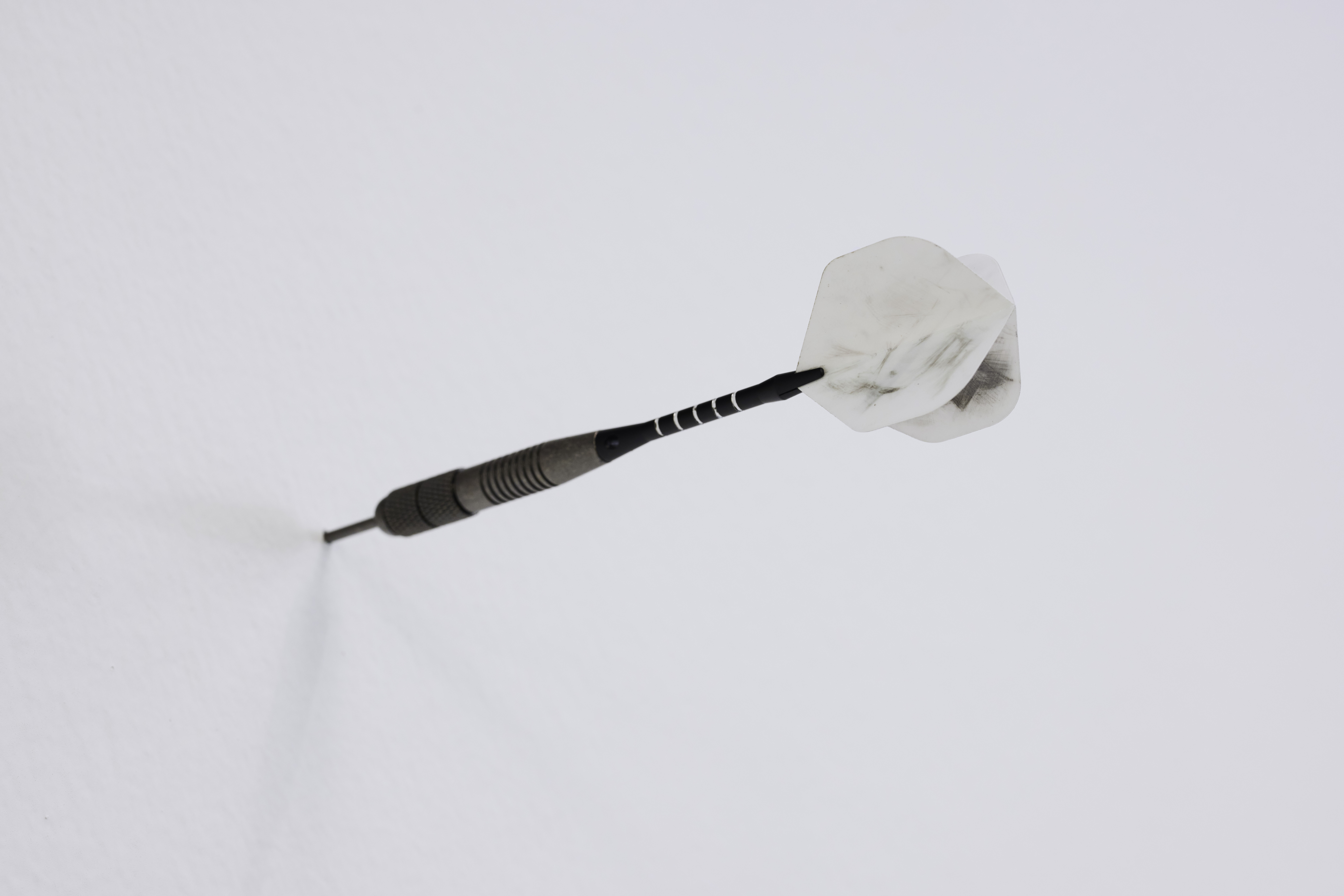 a dart stuck into a white wall