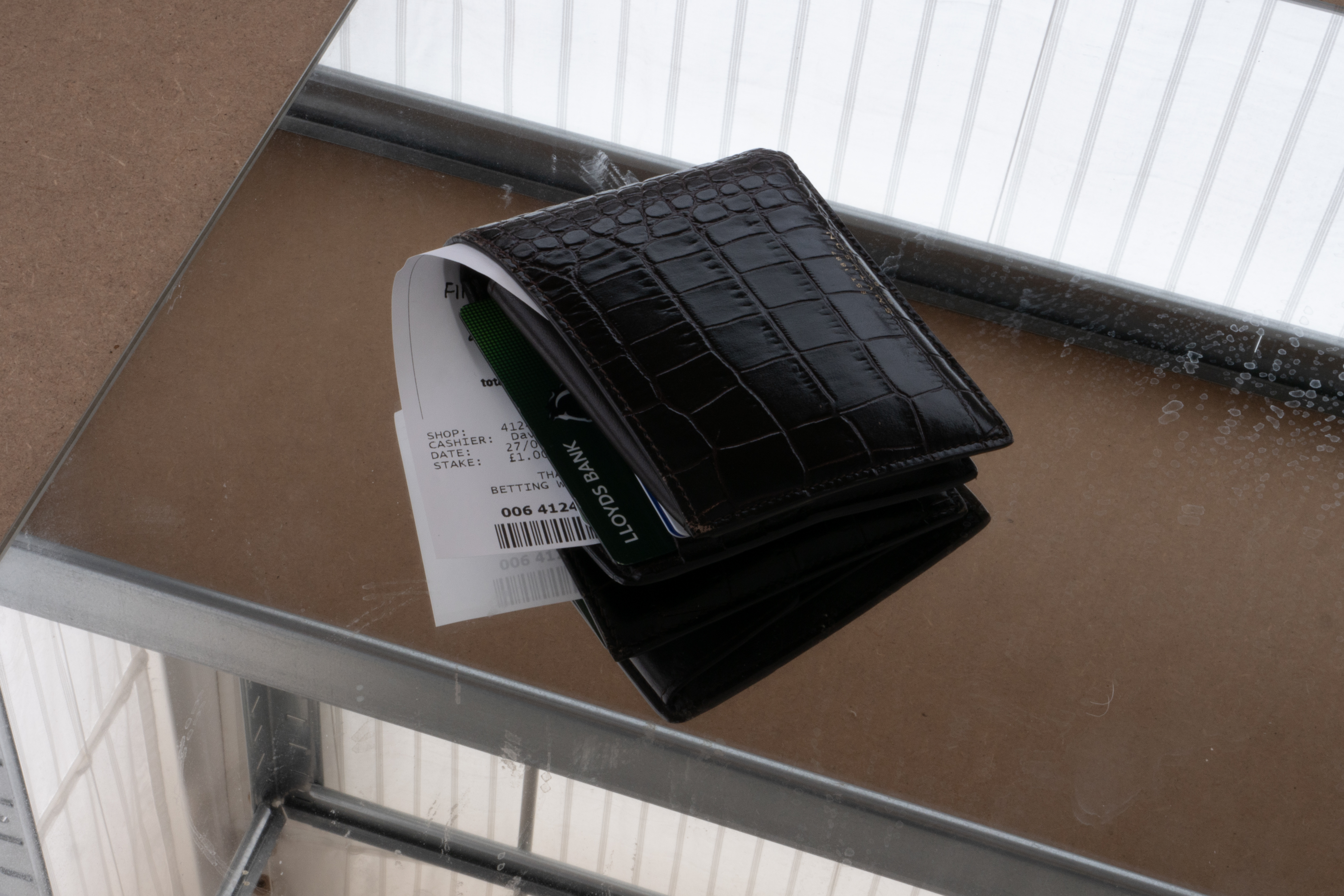 leather wallet with betting slip and bank card visible